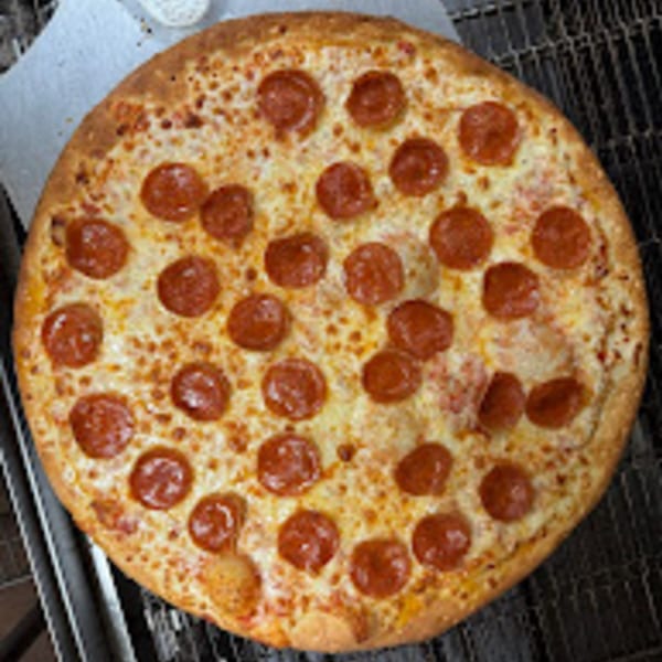 A whole, freshly baked Brooklyn Pizza pepperoni pizza with melted cheese on a metal rack.