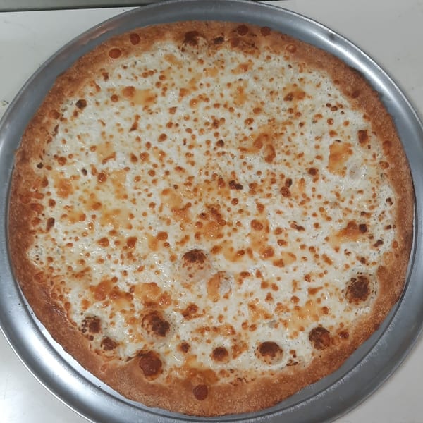 A freshly baked Brooklyn Pizza white pizza with melted cheese and a golden crust on a metal pan.