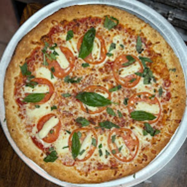 A Brooklyn Pizza Margherita, topped with fresh mozzarella, sliced tomatoes, and basil leaves.