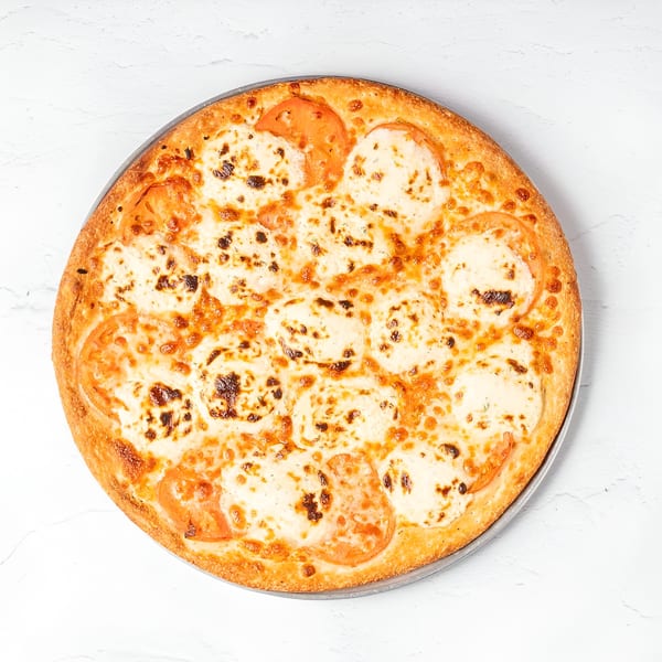 A whole Brooklyn Pizza with melted cheese and sliced tomatoes on a white background.